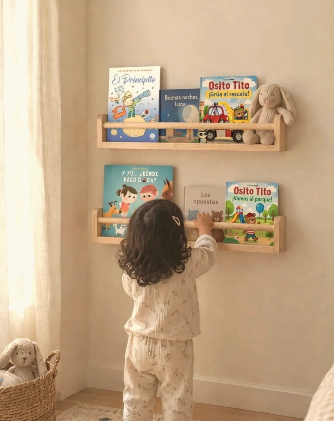 Una niña toma un cuento de dos repisas de madera colgadas a su altura, con los libros de frente.